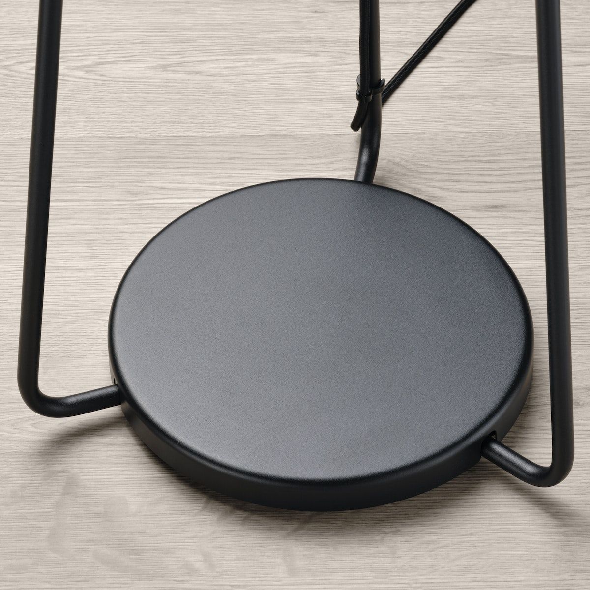 The base of a tripod holding up a speaker lamp. 
