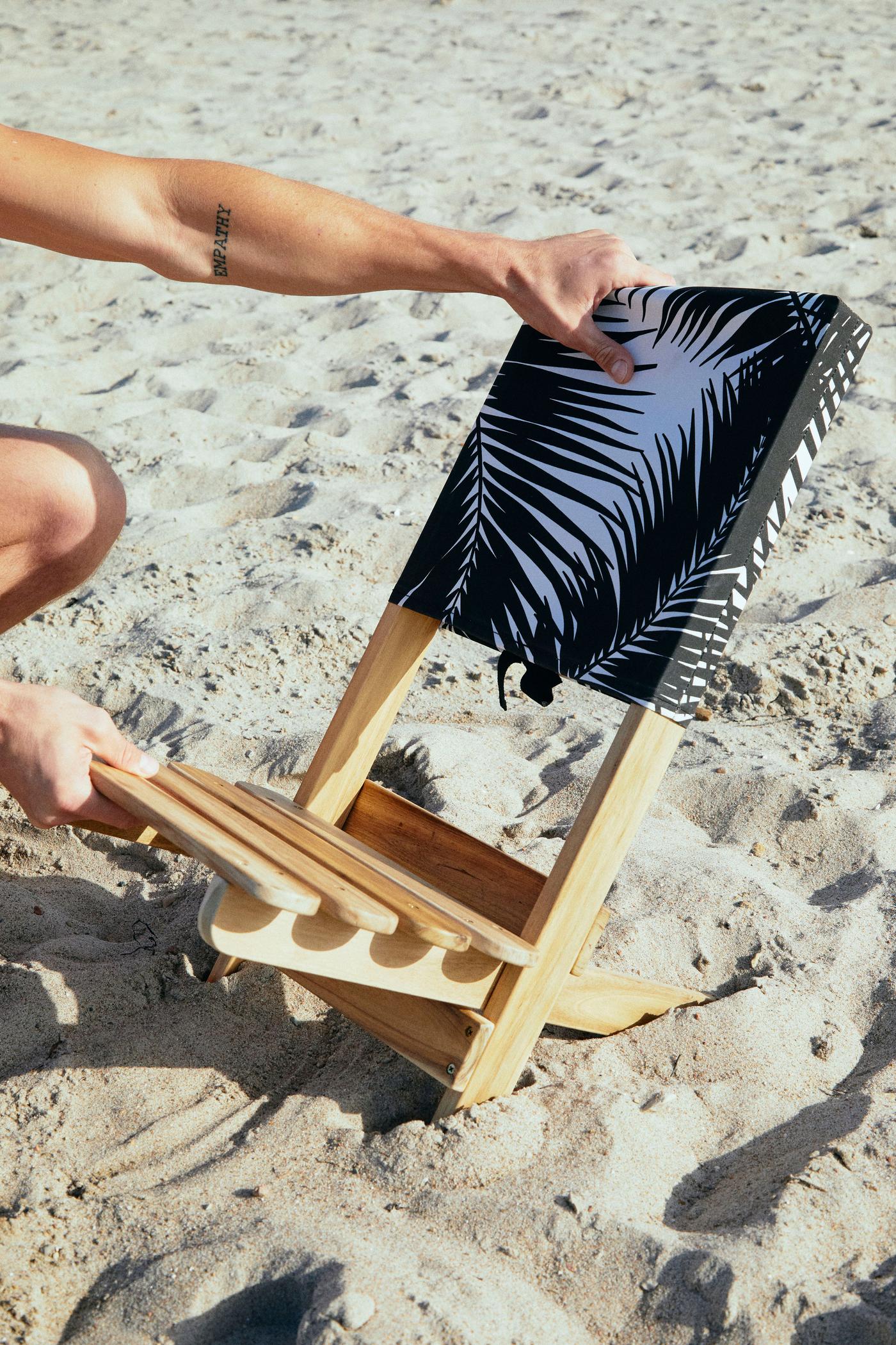A beach chair being set up at the beach.