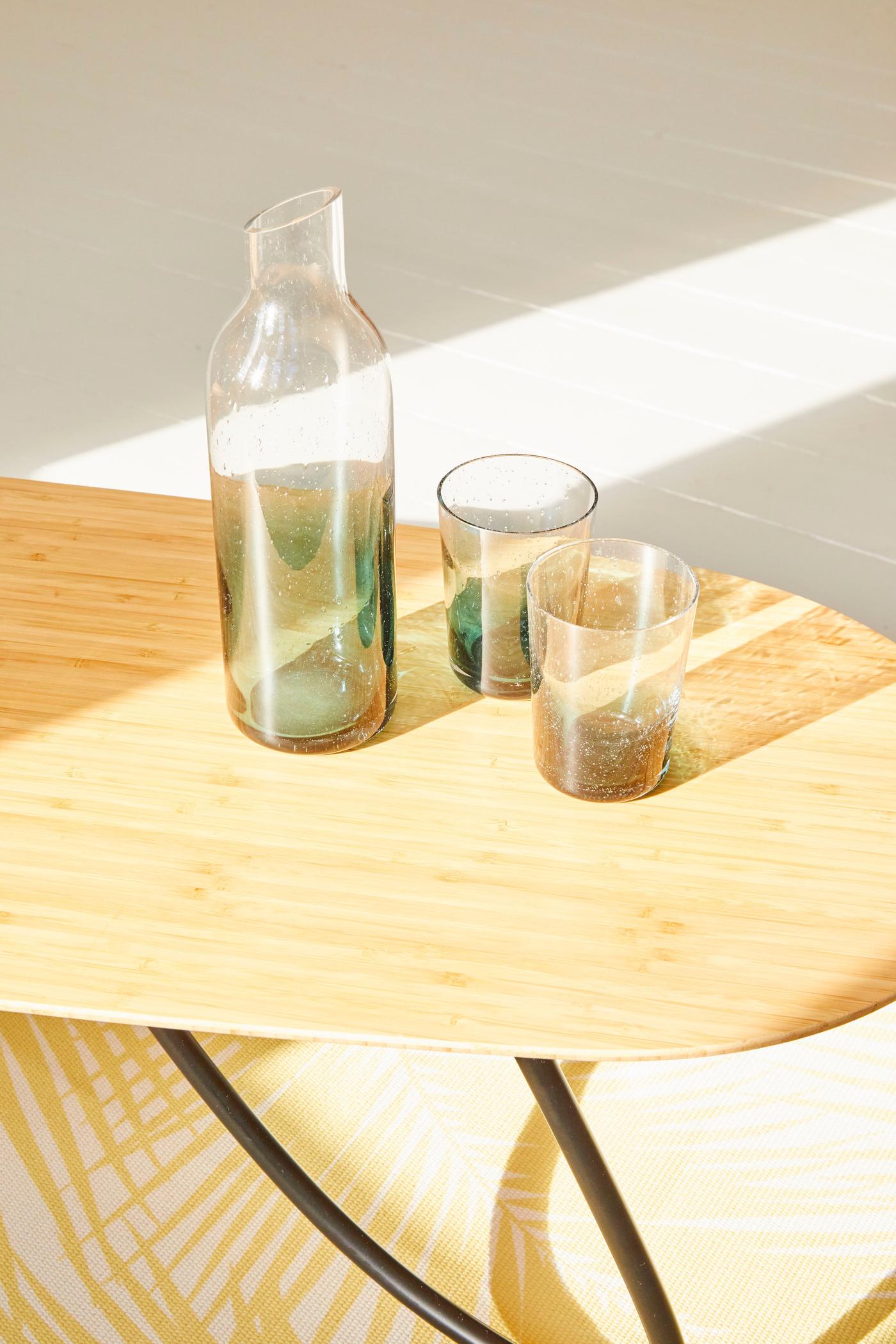 A wooden table with a bottle of water and two glasses.