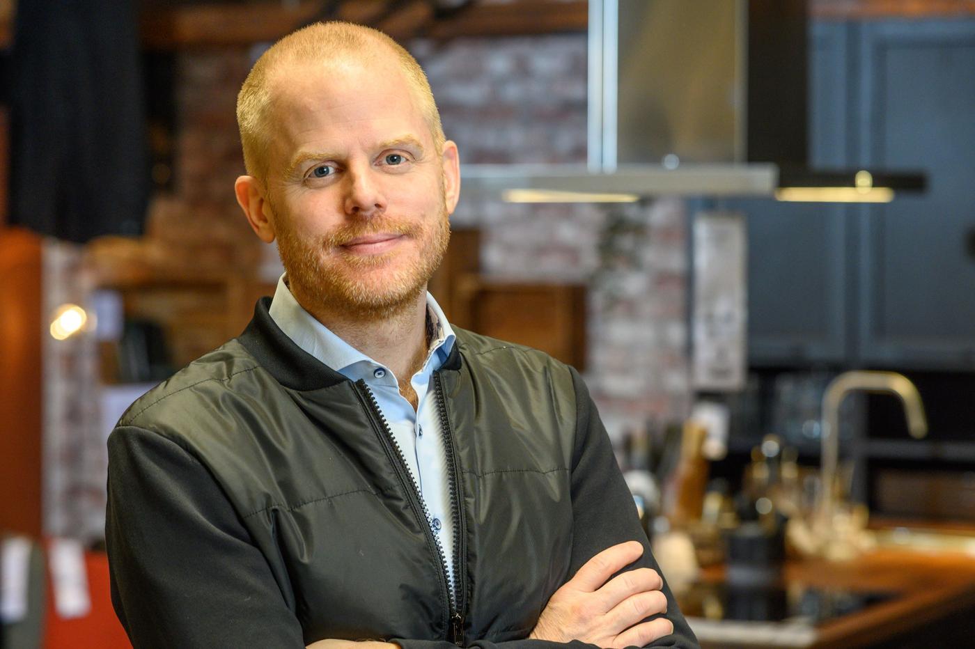 Jon Abrahamsson Ring standing in a kitchen setting, looking at the camera with arms folded.