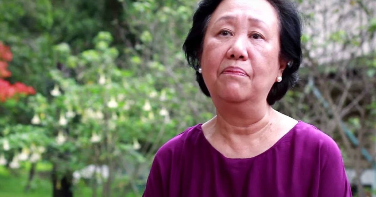 A woman against a background of greenery.
