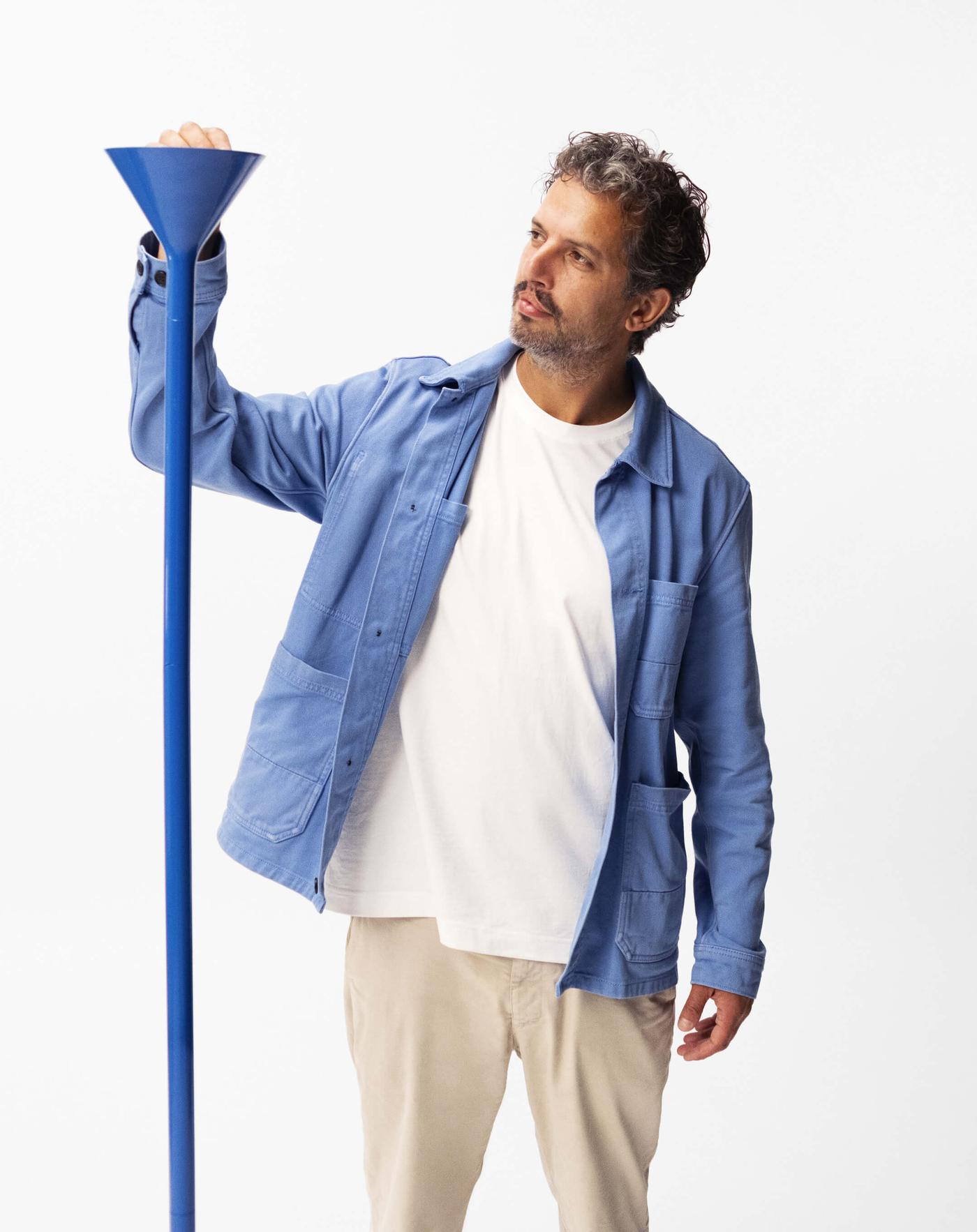 Designer Lex Pot stands next to a blue PS 2026 uplighter. He adjusts the lamp at the top.