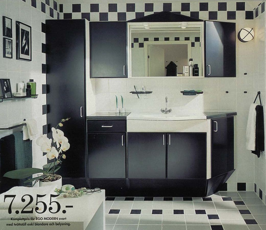 A black and white bathroom, featuring black cupboards, with black and white tiles.