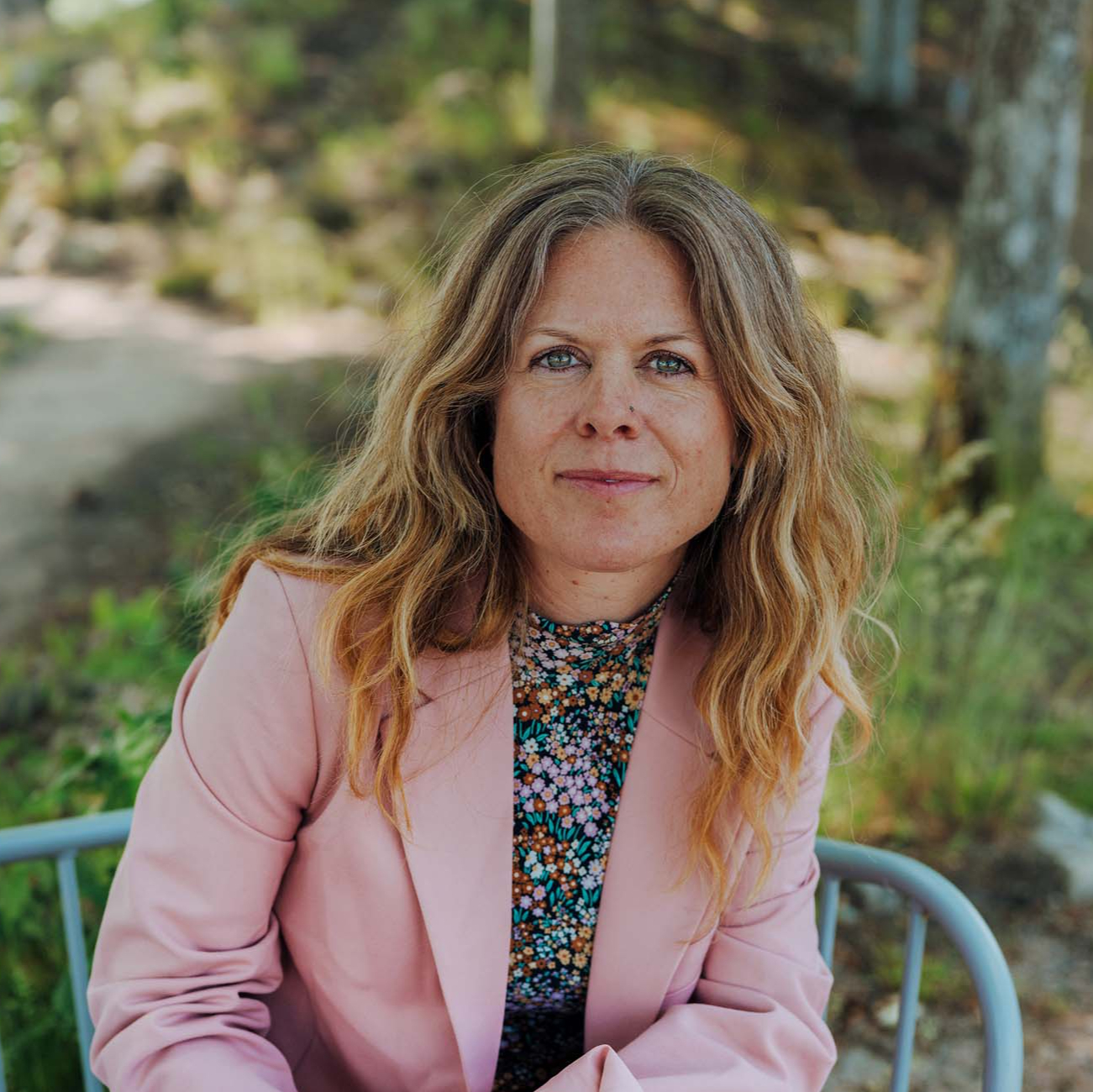 Interior designer Emilia Ljungberg, sitting on a bench, looking straight at the camera.