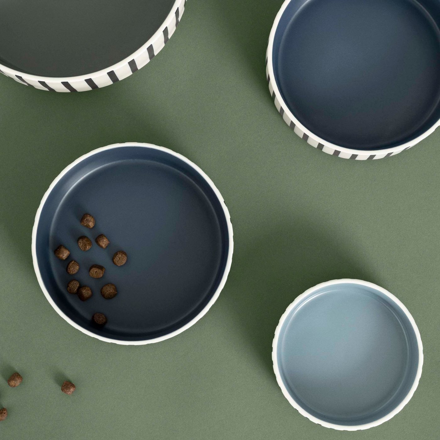 Collection of four blue and green pet bowls on a green background.