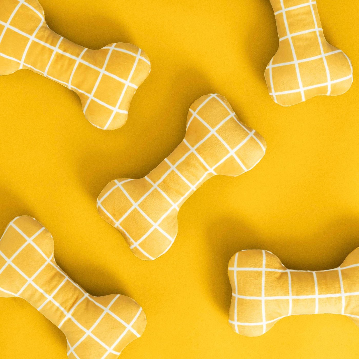 A collection of yellow soft toy bones on a yellow background.
