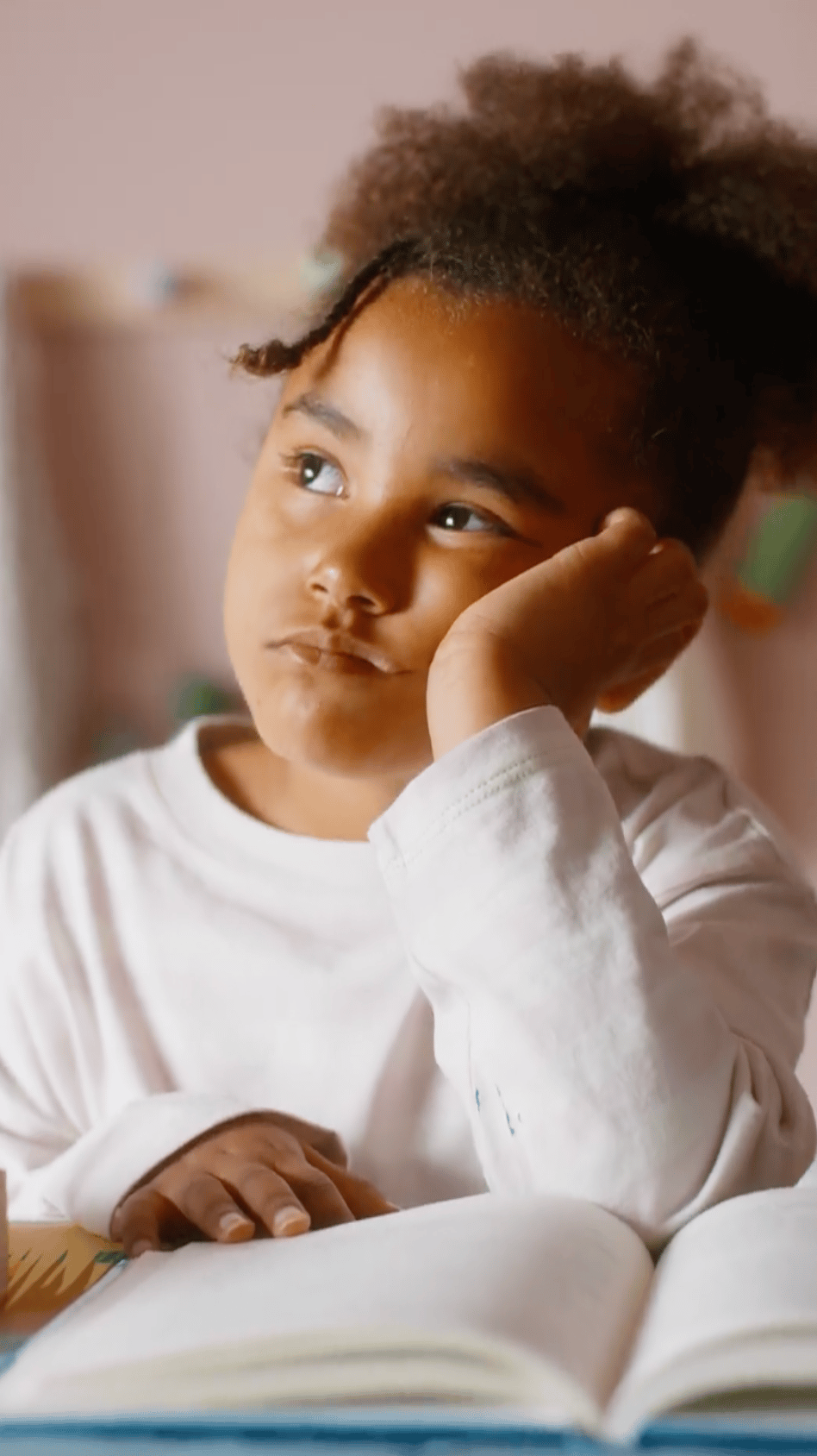 A child daydreaming at their desk with homework.