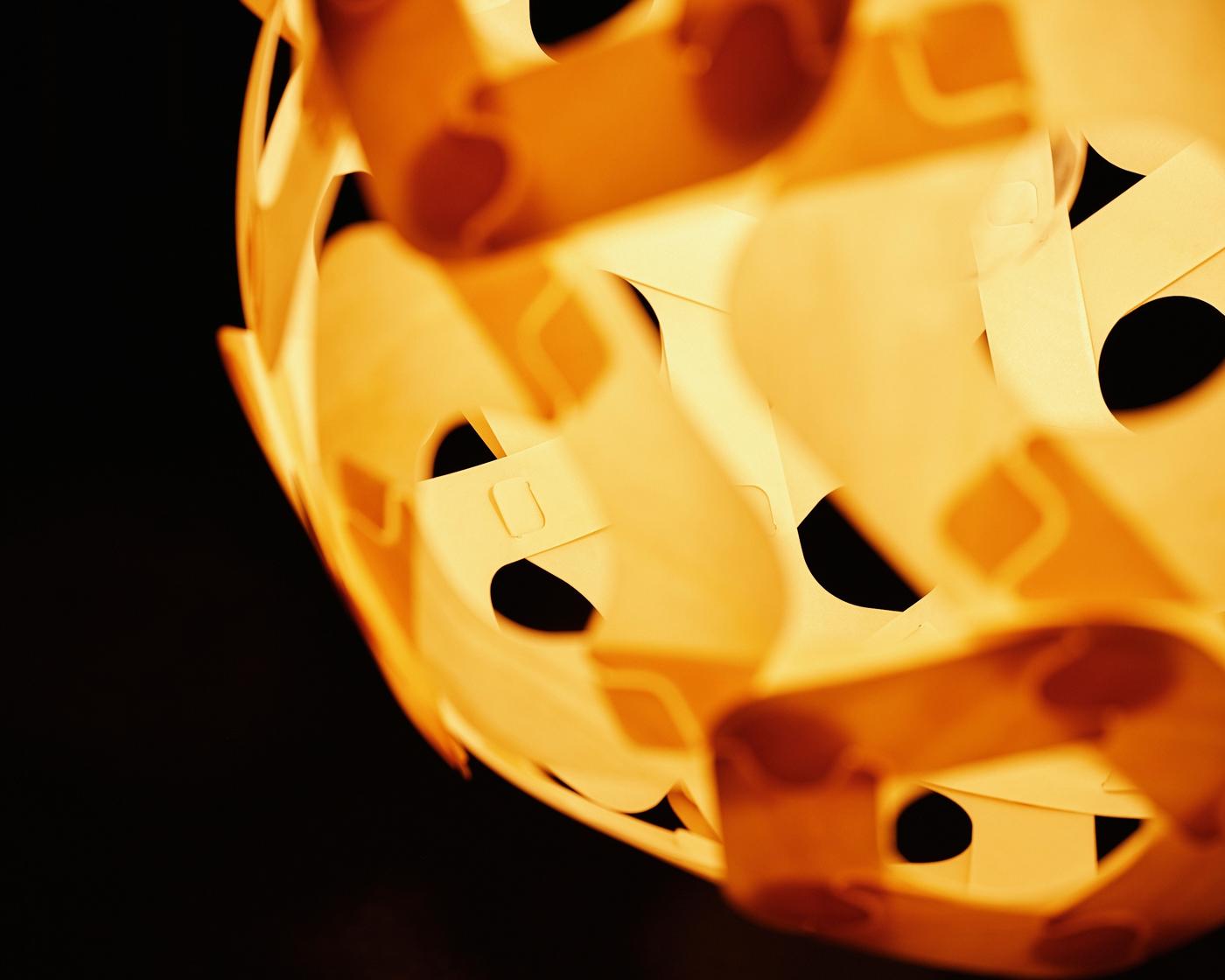 A close-up of a lit ÖDLEBLAD shade in a dark room.