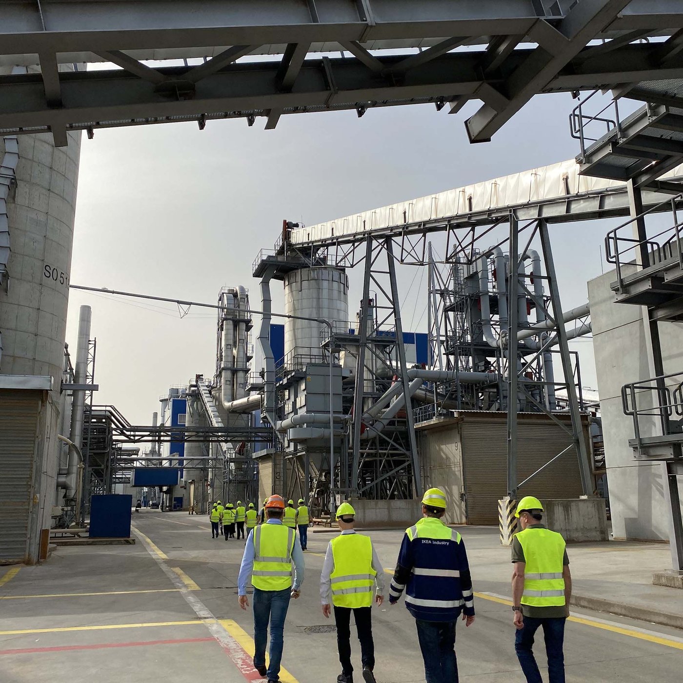 Four people walk past machinery at an IKEA Industry factory in Slovakia.