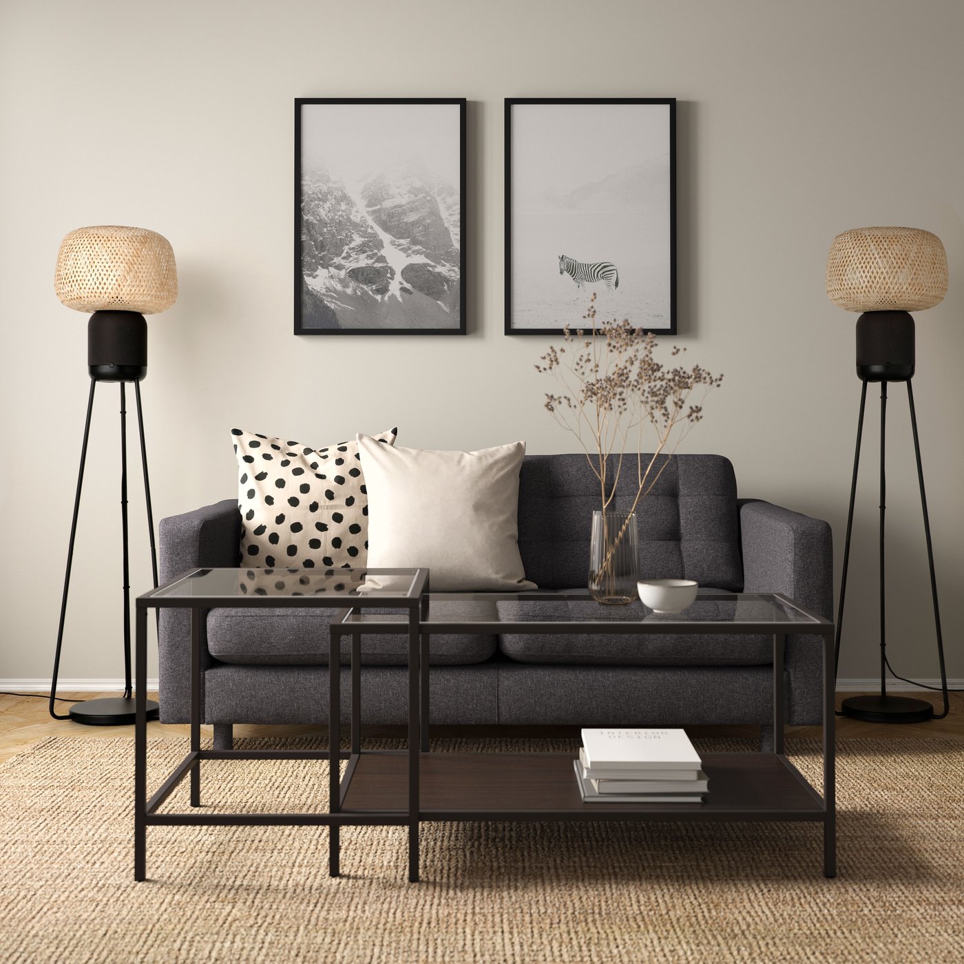 A living room with a sofa, a sofa table and two floor lamp speakers.
