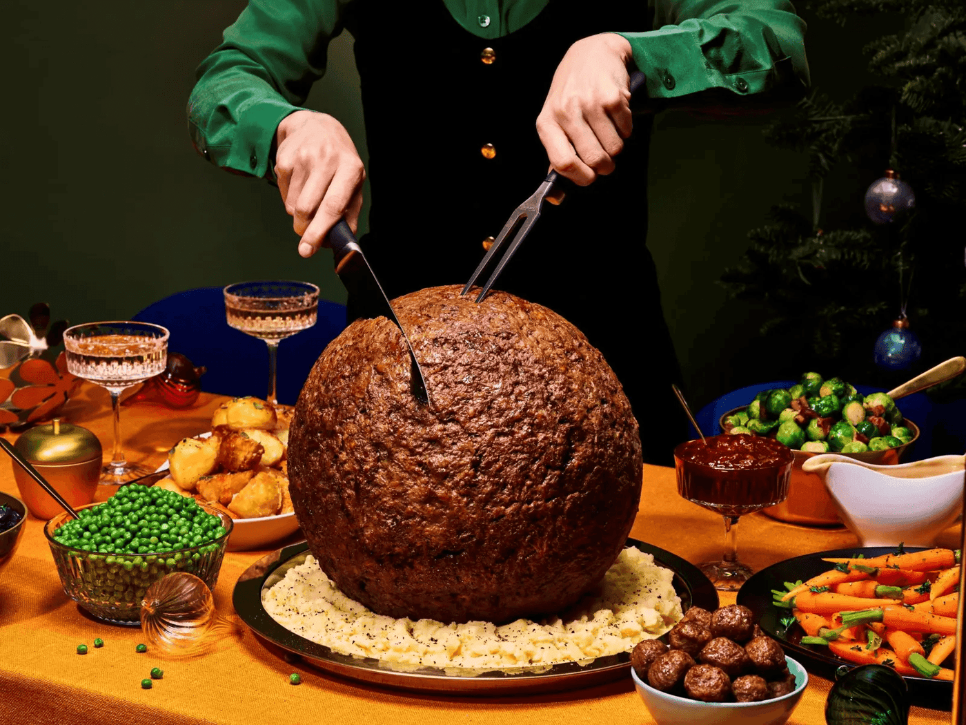 A giant meatball being carved on a Christmas table setting.