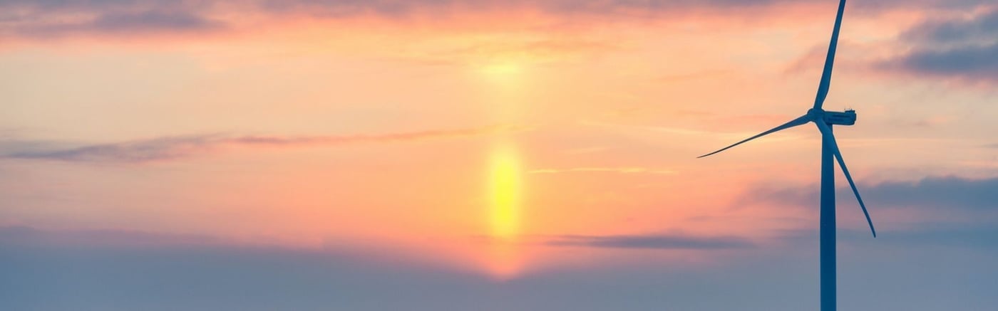A modern wind turbine silhouetted against a sunset.