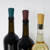 Tri boce vina s čepovima u boji: zelenom, crvenom i žutom, sprječavajući curenje i čuvajući okus.