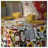 Svijetli, raznobojni cvjetni stolnjak sa žutim posuđem.