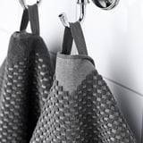 Dva ručnika uredno vise na kuke, jedan tkan s uzorkom sprijeda i obična stražnja strana, praktičan za upotrebu u kupaonici.