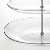 Stakleni stalak za posluživanje s čeličnim nosačima, naslagani tanjuri.