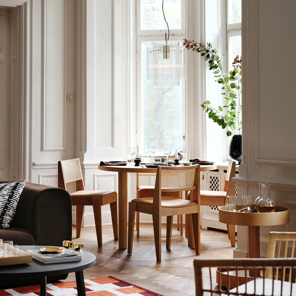 Moderna blagovaonica s drvenim stolom, tamnim kaučem, velikim prozorom i elegantnim lusterom.