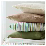 Hrpa raznobojnih jastuka; odozgo prema dolje: bijela, bež, prugasta, zelena. Mekana, pamučna tkanina s rubovima s resama.