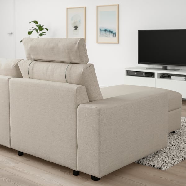 Moderna bež VIMLE sofa s podesivim naslonom za glavu, velikim naslonima za ruke i integriranim spremištem. Smješten pored televizora ravnog ekrana.