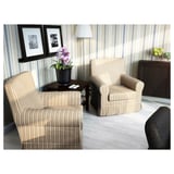 Modern nappali csíkos fotelekkel, fa asztallal és lámpával. A dekoráció fényképeket, orchideákat és gyümölcstálat tartalmaz.