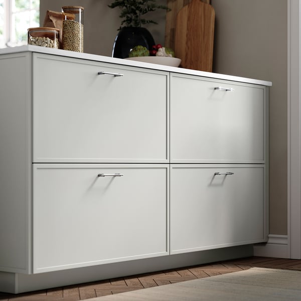 Fehér ASPUDDEN konyhaszekrények; elegáns, modern dizájn. Magasan áll, szélesebb, mint a falra akasztó vágódeszka, tágas fiókokkal.