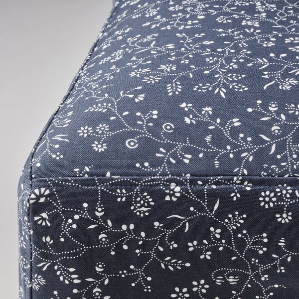 Közeli kép a kárpitozott székről, bonyolult fehér virágmintával, sötét anyagon, részletgazdag kivitelezéssel.