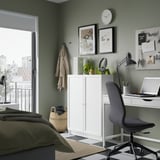 Irodasarok a hálószobában: szürke szék, fehér íróasztal, BILLY könyvespolc, zöld fal, kilátás az erkélyre, dekorációk.