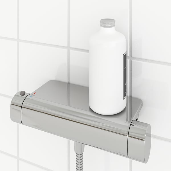 Modern krómozott termosztatikus zuhanycsaptelep beépített polccal, amely egy palackot tartalmaz. Ez egy biztonsági ütköző 38°C-on és hideg tapintású felület.