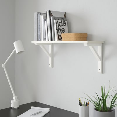 Minimalista fehér fali polc - BURHULT, könyvek tárolására alkalmas, kis doboz, falra szerelhető az íróasztal fölé. Lámpa és növény mellette. A polc kicsi, a könyvek magasabbak.