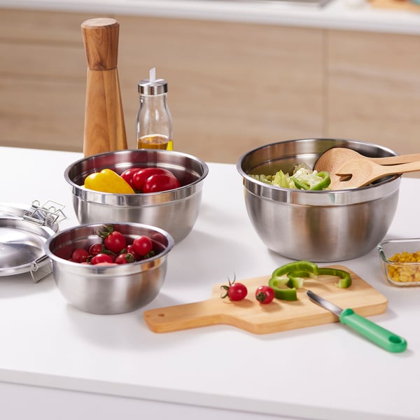 Rozsdamentes tálak fedéllel az ételek elkészítéséhez, tálalásához és tárolásához. Különböző méretű fészek a könnyű tárolás érdekében. Friss zöldségekkel és vágódeszkával látható.