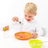 A gyermek narancssárga tálból eszik rozsdamentes acél villával. Mosogatógépben mosható, 3+ éves kor. Világos, szórakoztató, gyerekbarát.