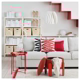 Modern nappali szürke FÖRLUNDA kanapéval, piros díszítéssel és minimalista dekorációval.