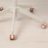 Közeli kép egy modern irodai szék alapjáról és kerekeiről, letisztult kialakításról, sima görgőkről.