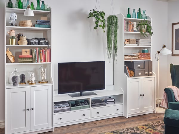 Modern nappali HAUGA fehér szekrénnyel, tv-vel, könyvekkel, dekorációval, növényekkel.