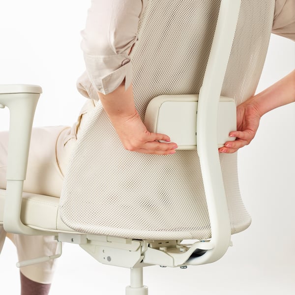 Ergonomikus irodai szék deréktámaszát beállító személy.