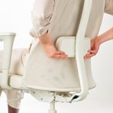 Ergonomikus irodai szék deréktámaszát beállító személy.