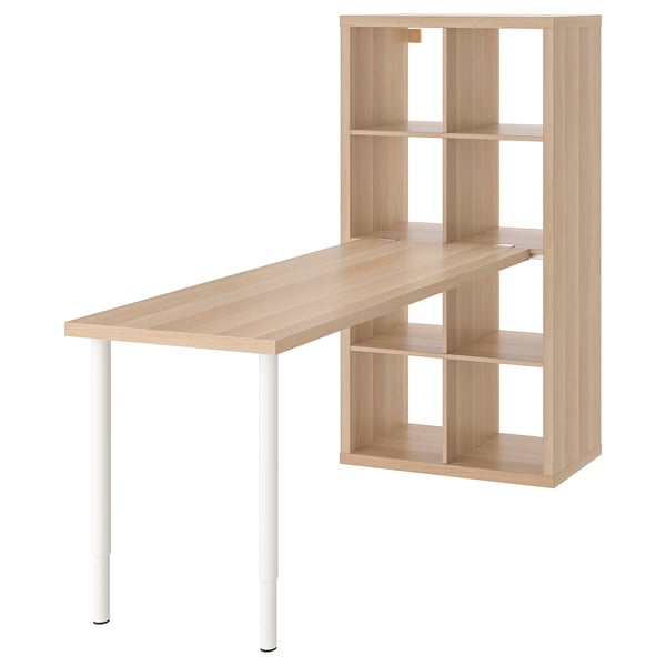 Egy ikea KALLAX egység egy könnyű fa íróasztallal. Az egység több polccal rendelkezik a tároláshoz, az íróasztalt pedig fehér lábak támasztják alá.