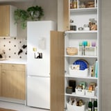 Modern konyha nyitott szekrényben, tálakkal, csészékkel, edényekkel és könyvekkel, fa előlappal.