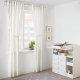 Világos gyerekszoba fehér dekorációval, szív/pillangó művészettel, pöttyös szőnyeggel.