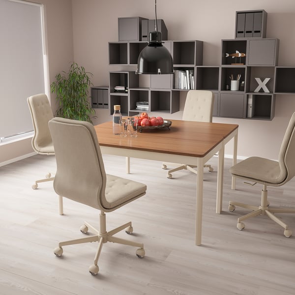 Modern iroda MULLFJÄLLET forgószékkel, fa íróasztallal, gyümölccsel, polcokkal, növényekkel, rózsaszín falakkal.