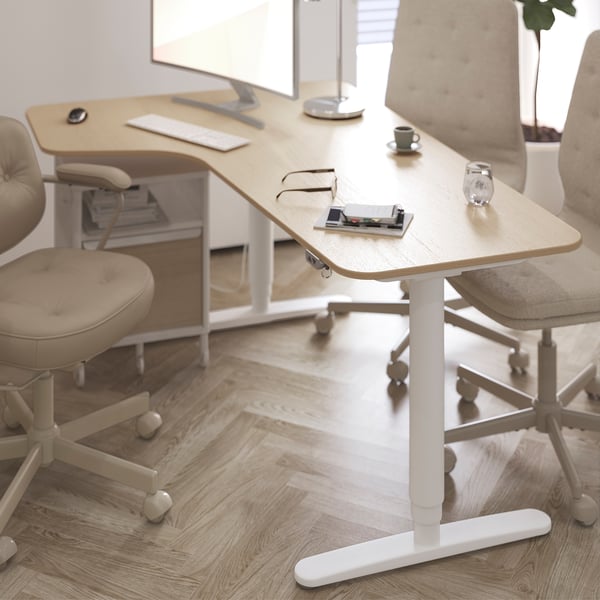 Modern otthoni iroda bézs színű MULLFJÄLLET forgószékekkel, fából készült íróasztallal, monitorral, billentyűzettel és kávéscsészével.