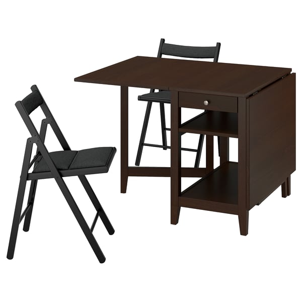 Barna NÄSINGE kompakt étkezőgarnitúra sötét fa asztallal és két fekete összecsukható székkel. Az asztalon lehulló levelek és tárolópolc található.
