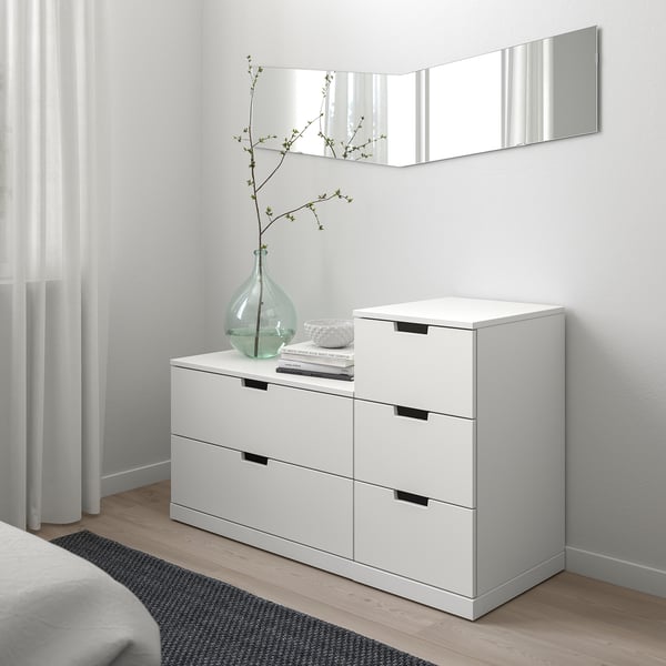 Modern fehér NORDLI láda 6 fiókkal és növényi vázával a tetején.