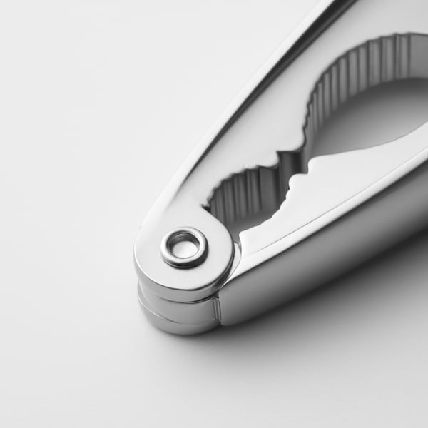 Ezüst konyhai eszköz markolattal és csuklópánttal, diófélék vagy kagylók feltörésére tervezték, közelről rögzítve.