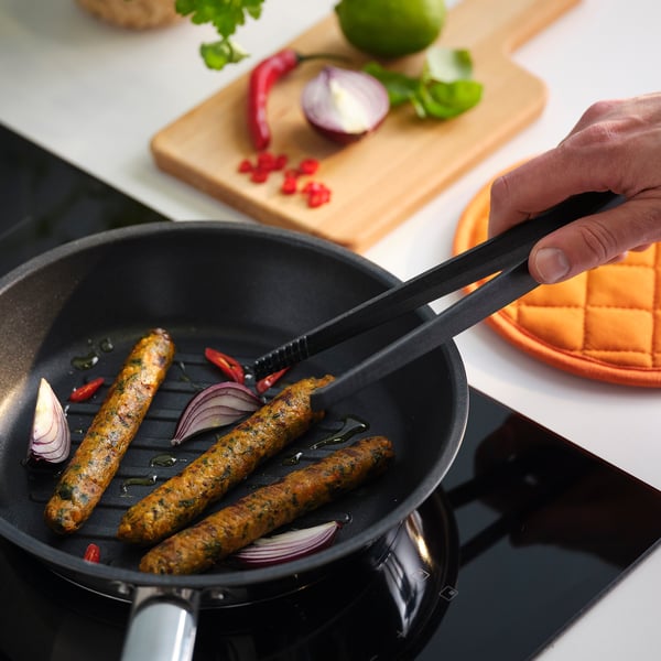Kolbász főzése zöldségekkel egy serpenyőben