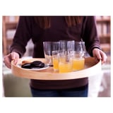 Egy személy, aki nyírfa tálcát visz poharakkal és süteményekkel.