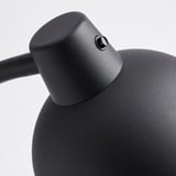 Közeli kép a modern fekete lámpáról. Texturált, masszív kialakítás. Rugalmas illesztések a beállításhoz. Szilárd fémszerkezet.