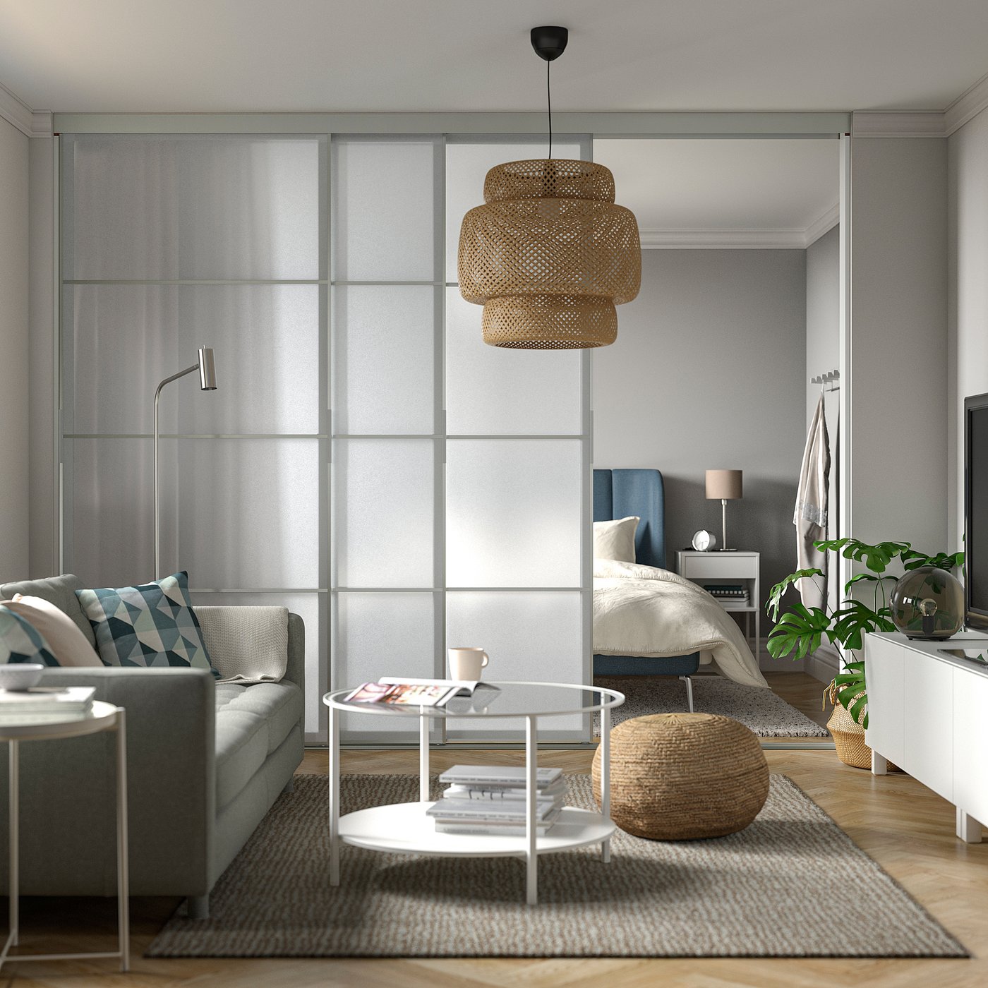 Modern stúdió apartman szürke SKYTTA tolóajtóval, franciaággyal, szürke kanapéval, dohányzóasztallal, fonott lámpával, növényekkel, minimális dekorációval.