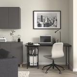 Modern otthoni iroda SPÄND íróasztallal, szürke székkel, városképpel, laptoppal és kanapéval.