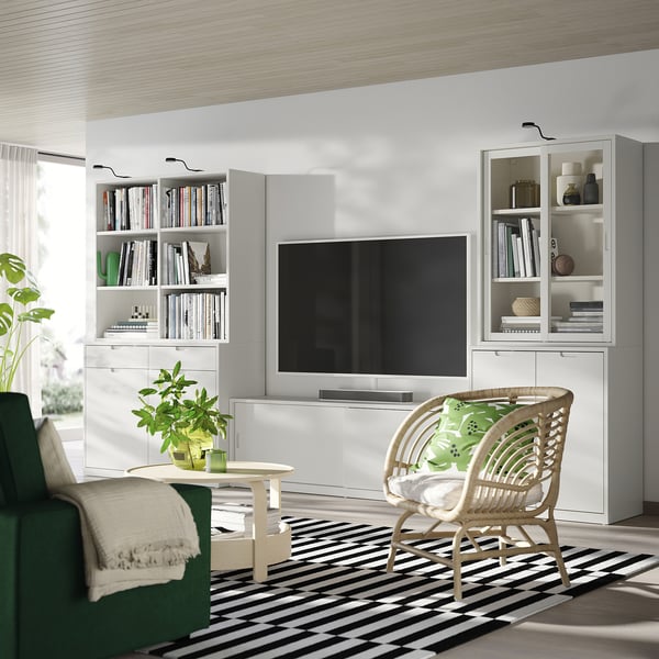 Modern, törtfehér TONSTAD nappali szett elegáns tv-vel, könyvespolcokkal, fonott székkel és zöld kanapéval. Világos, minimalista dizájn.